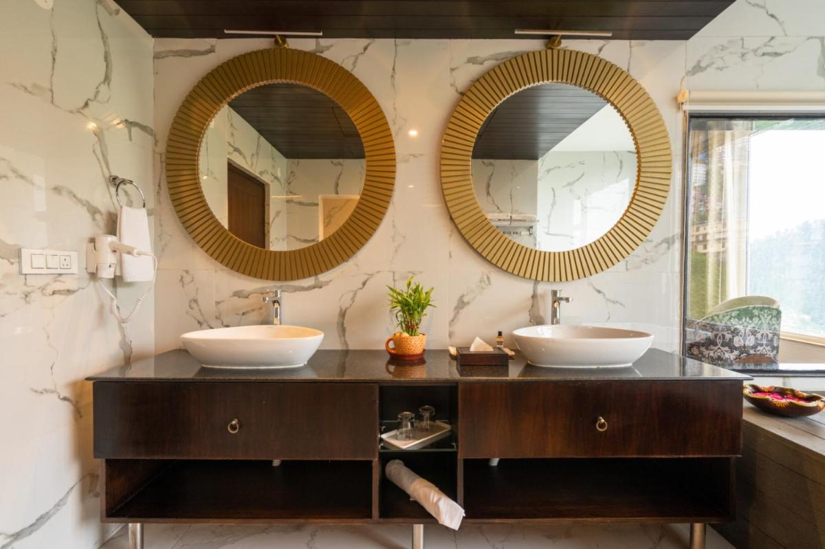 two sinks in a bathroom with two mirrors at The Orchid Shimla in Shimla