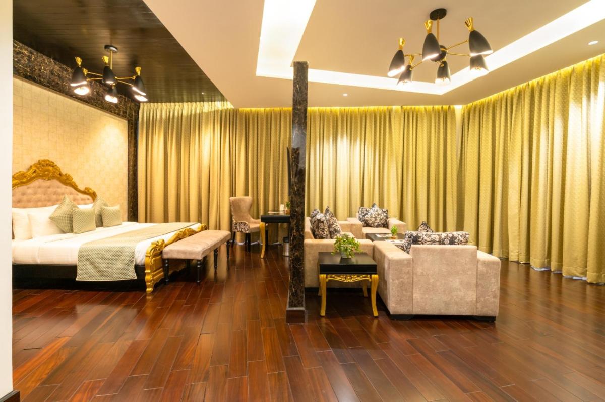 a hotel room with a bed and a couch and chairs at The Orchid Shimla in Shimla