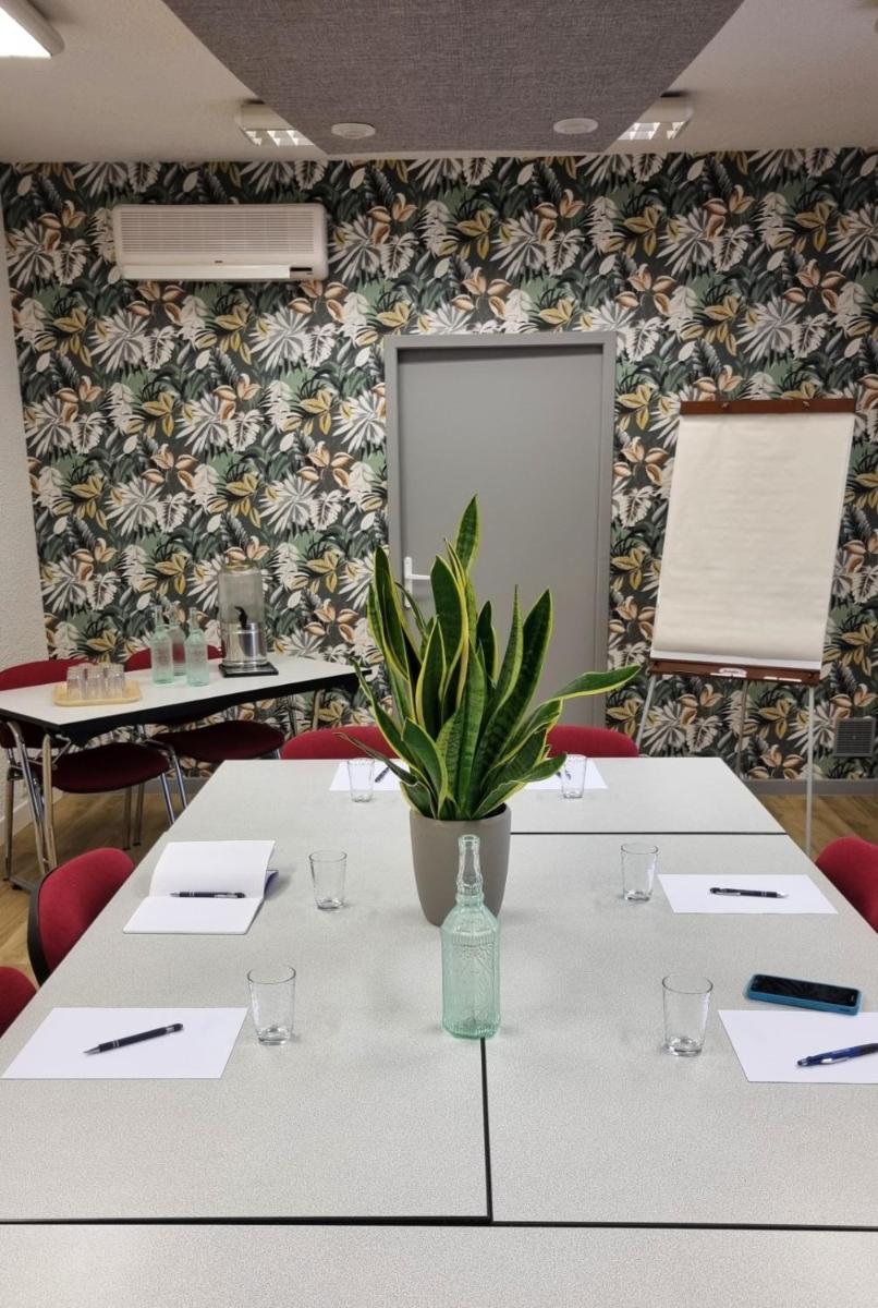 une salle de réunion avec des tables blanches et une plante en pot dans l'établissement Logis Hotel Le Tropicana, à Douville 37 autres photos