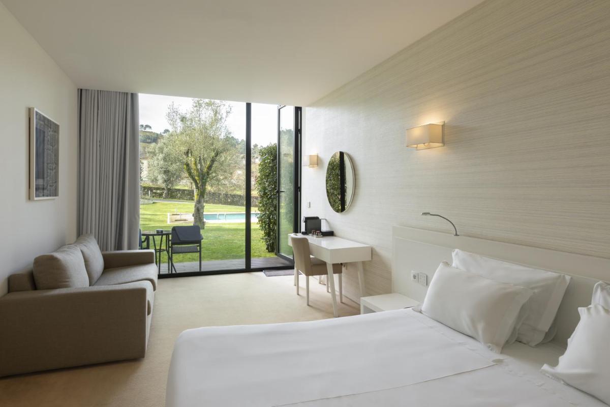 um quarto de hotel com uma cama, uma escrivaninha e um sofá em Tempus Hotel & Spa em Ponte da Barca mais 60 fotografias