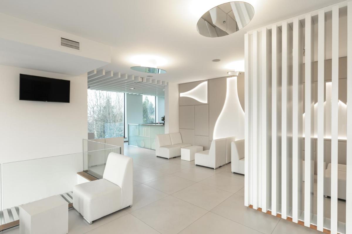 uma sala de estar com cadeiras brancas e uma televisão em Tempus Hotel & Spa em Ponte da Barca