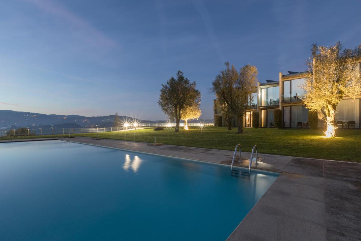 uma piscina em frente a uma casa à noite em Tempus Hotel & Spa em Ponte da Barca uma piscina em frente a uma casa à noite em Tempus Hotel & Spa em Ponte da Barca