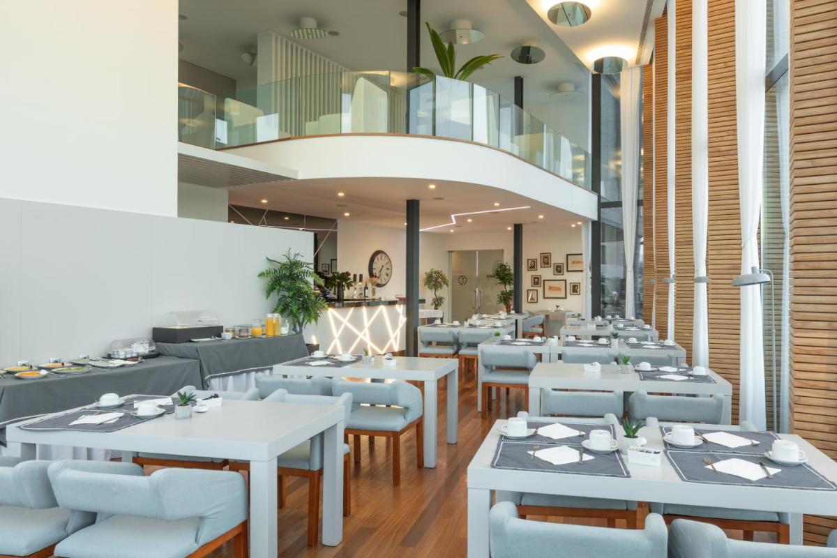 uma sala de jantar com mesas e cadeiras brancas em Tempus Hotel & Spa em Ponte da Barca