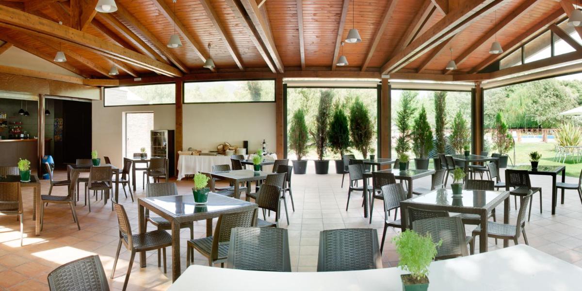 Un comedor con mesas y sillas y ventanas. en Hotel Balneario Valle del Jerte, en Valdastillas