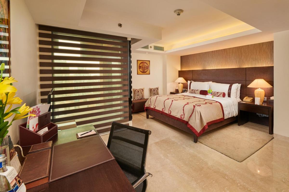 a bedroom with a bed and a desk and a table at The LaLiT New Delhi in New Delhi