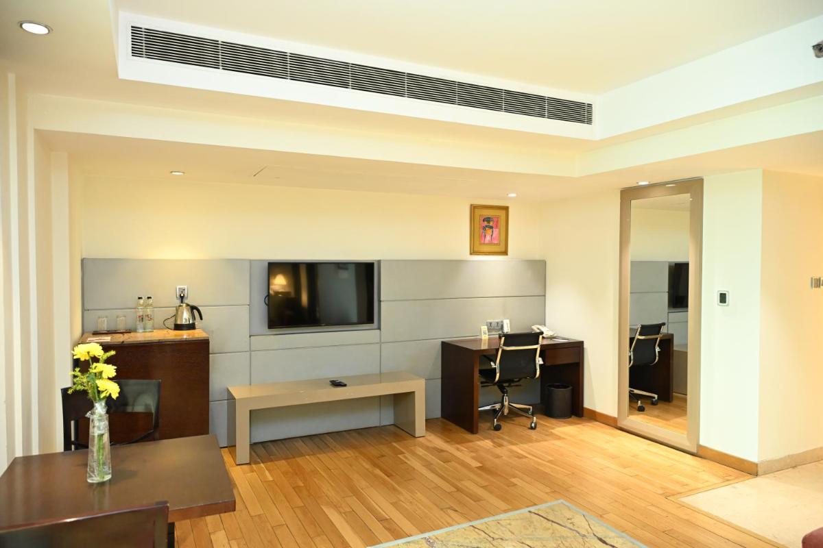 a living room with a television and a table and chairs at The LaLiT New Delhi in New Delhi