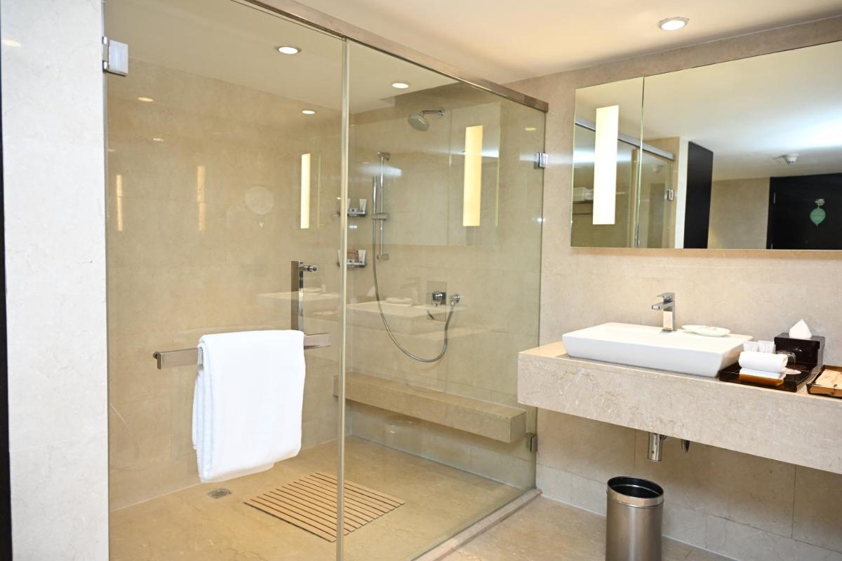 a bathroom with a glass shower and a sink at The LaLiT New Delhi in New Delhi