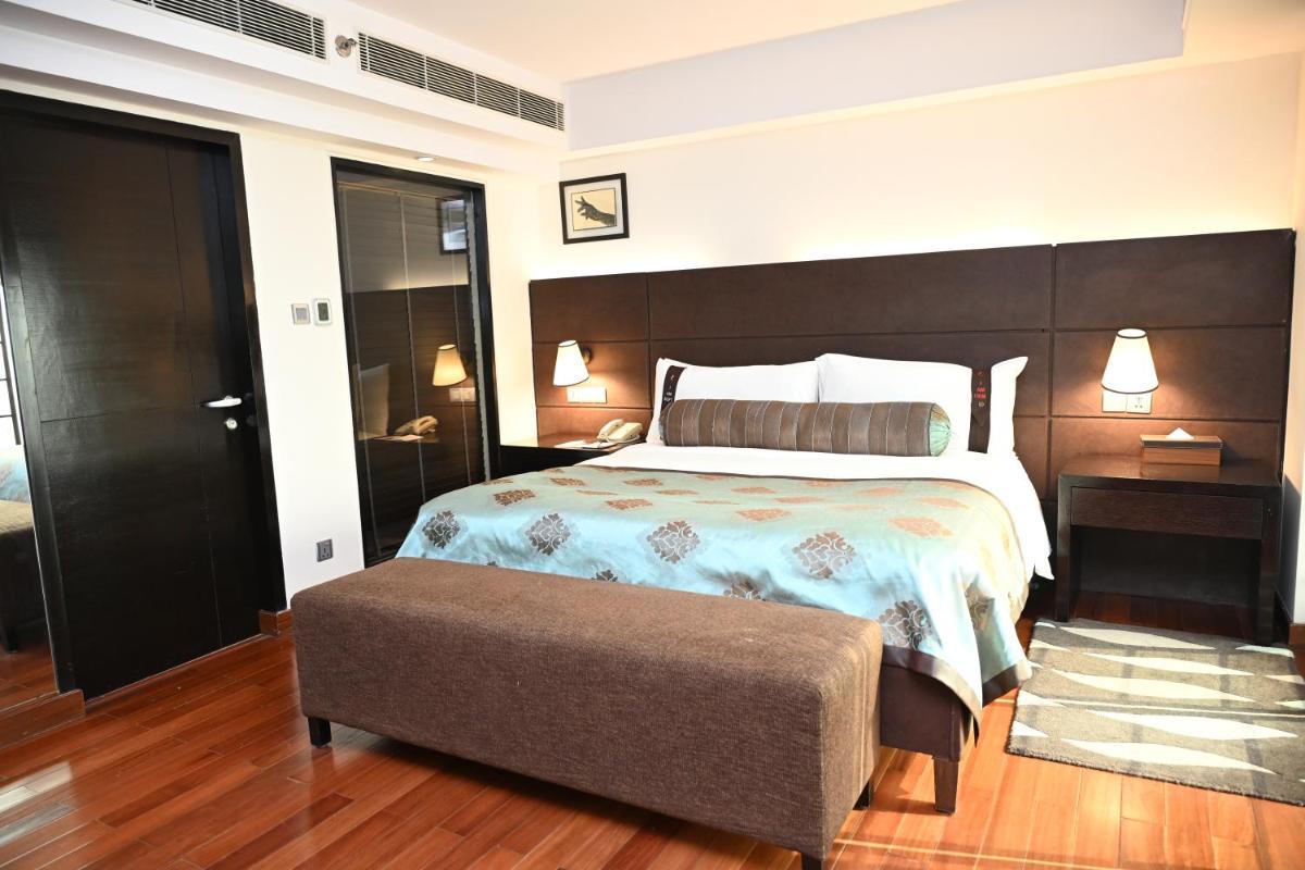 a bedroom with a large bed with a brown headboard at The LaLiT New Delhi in New Delhi