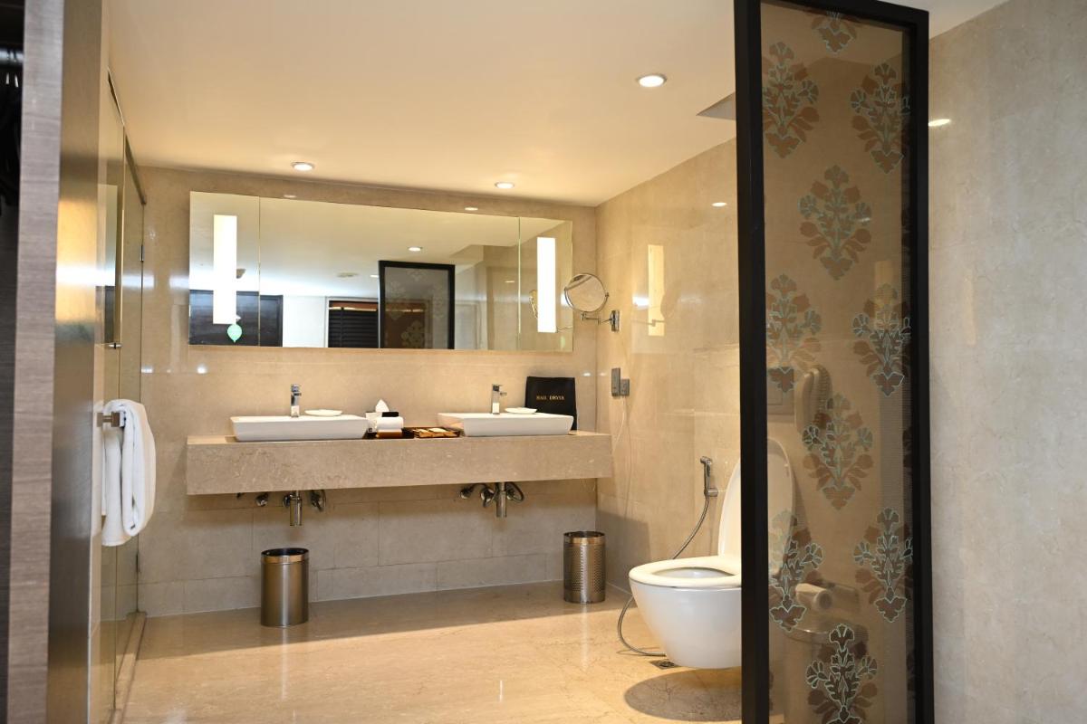 a bathroom with two sinks and a toilet and a mirror at The LaLiT New Delhi in New Delhi