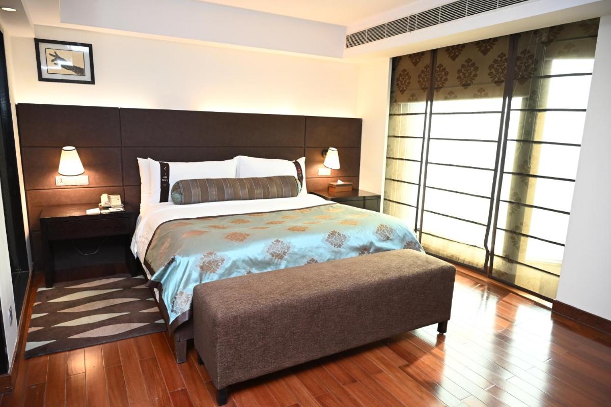 a bedroom with a large bed and a chair at The LaLiT New Delhi in New Delhi