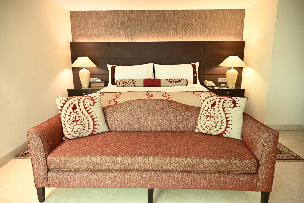 a bedroom with a bed with a couch in it at The LaLiT New Delhi in New Delhi