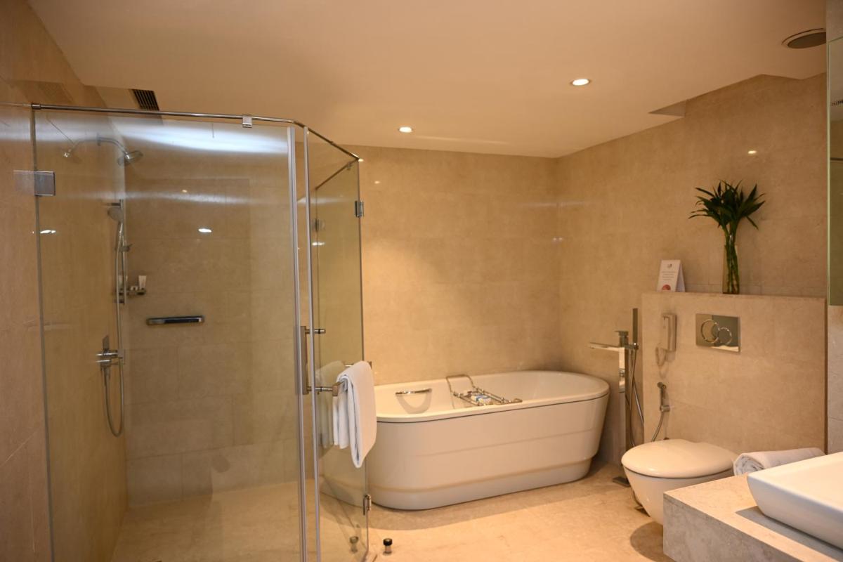 a bathroom with a tub and a shower and a toilet at The LaLiT New Delhi in New Delhi