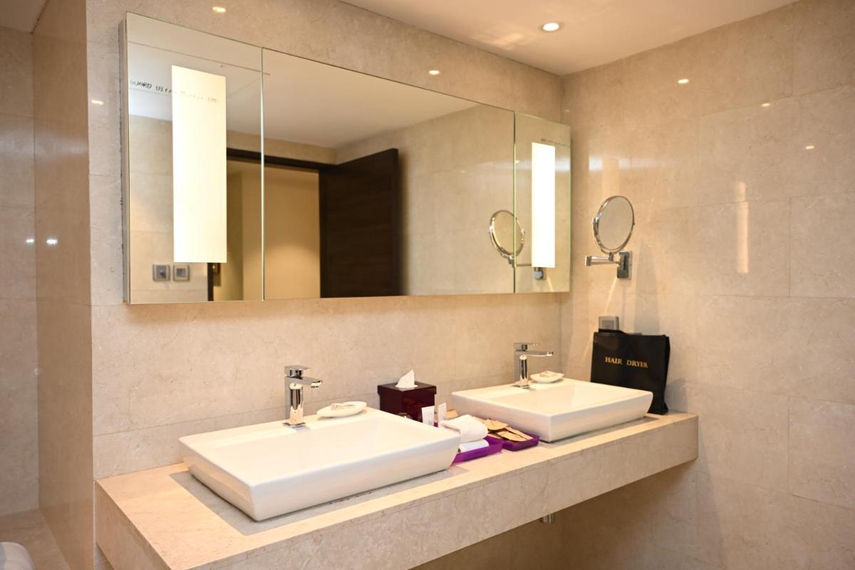 a bathroom with two sinks and a mirror at The LaLiT New Delhi in New Delhi