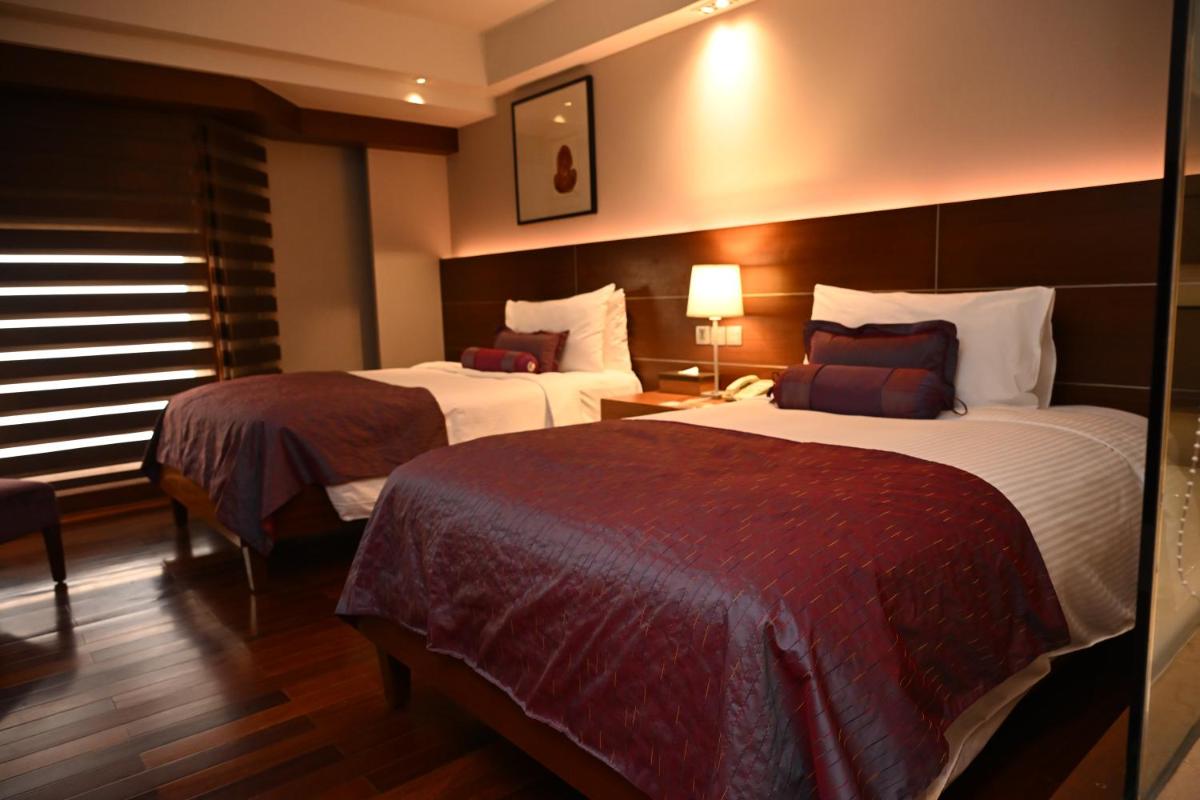 a hotel room with two beds and a window at The LaLiT New Delhi in New Delhi