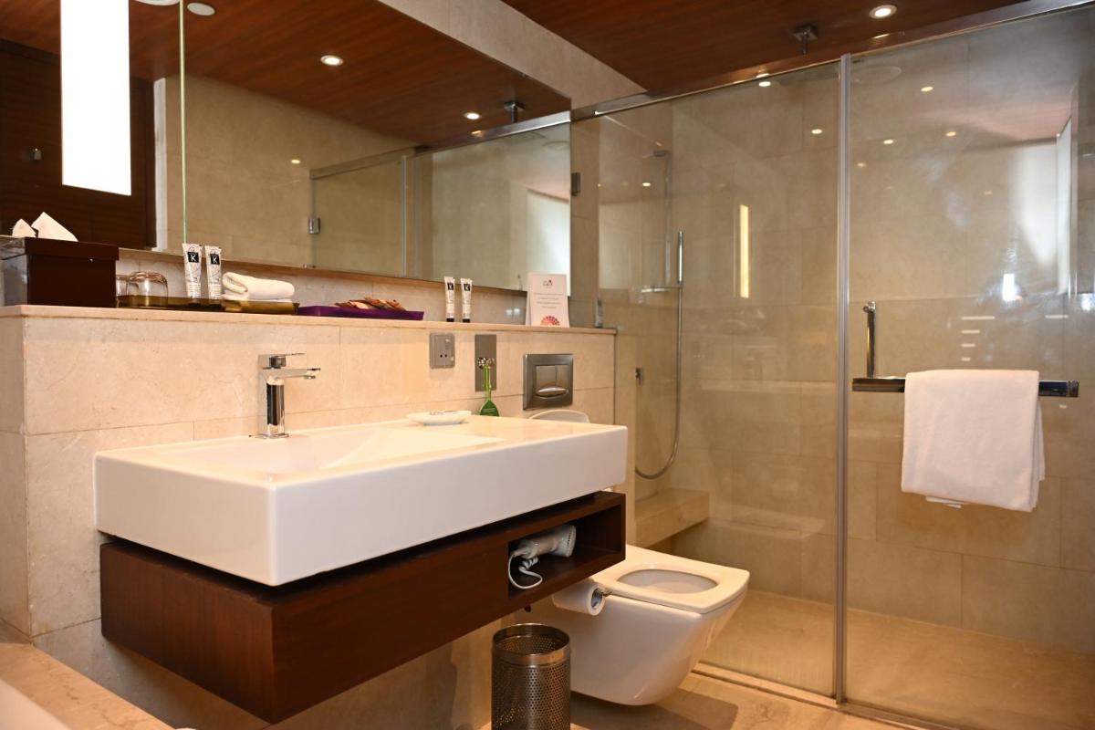 a bathroom with a sink and a toilet and a shower at The LaLiT New Delhi in New Delhi