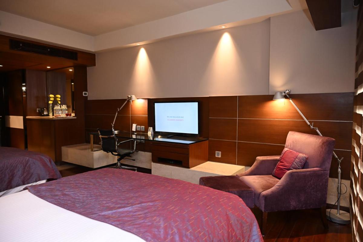 a bedroom with a bed and a flat screen tv at The LaLiT New Delhi in New Delhi