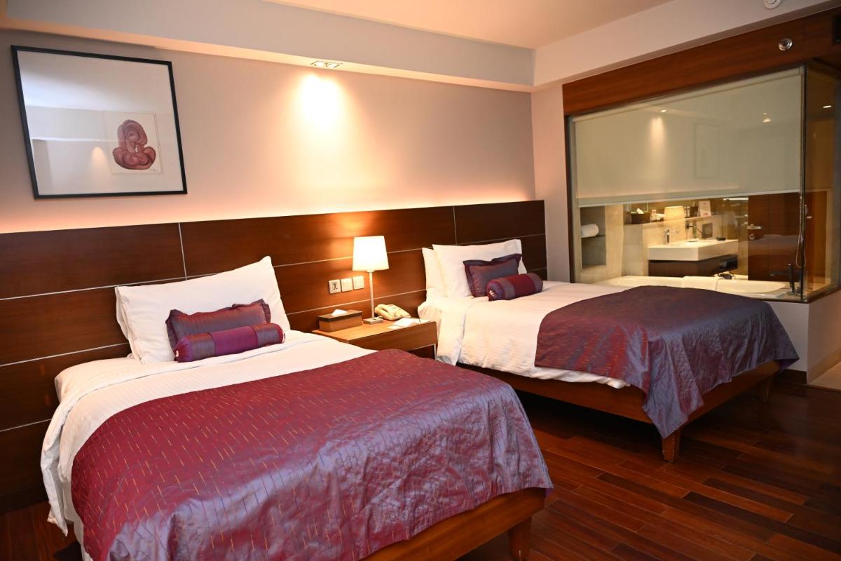 a hotel room with two beds and a mirror at The LaLiT New Delhi in New Delhi