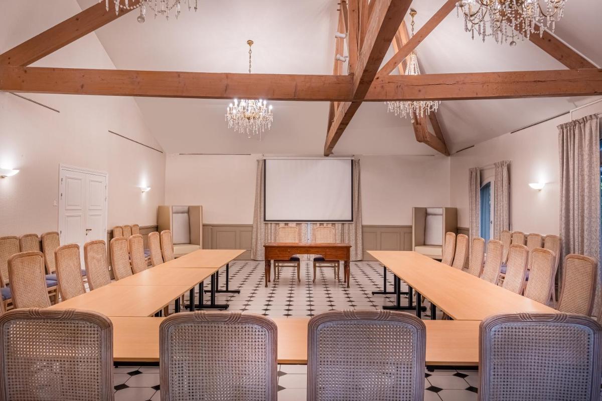 une salle de conférence avec des tables et des chaises en bois dans l'établissement Château des Reynats, à Chancelade 35 autres photos