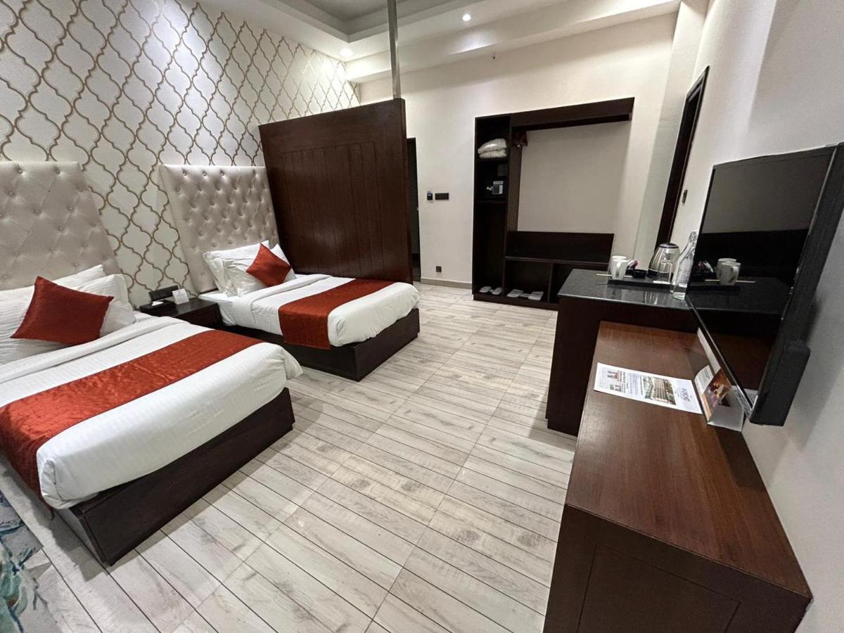 a hotel room with two beds and a desk at The Orchid Shimla in Shimla