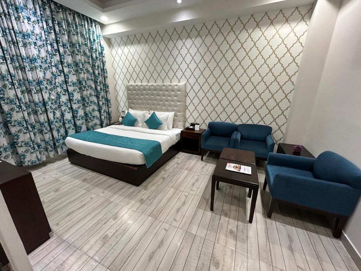 a bedroom with a bed and two blue chairs at The Orchid Shimla in Shimla