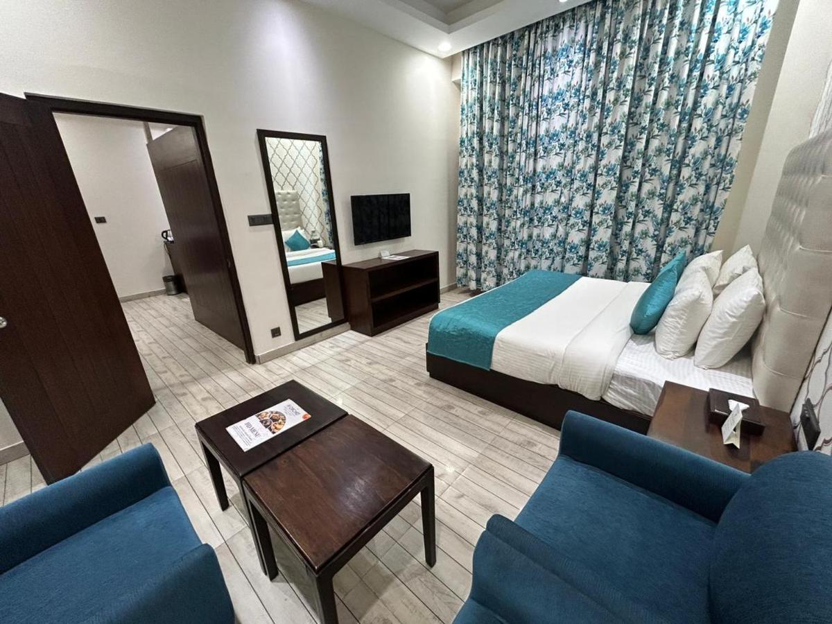 a hotel room with a bed and two blue chairs at The Orchid Shimla in Shimla