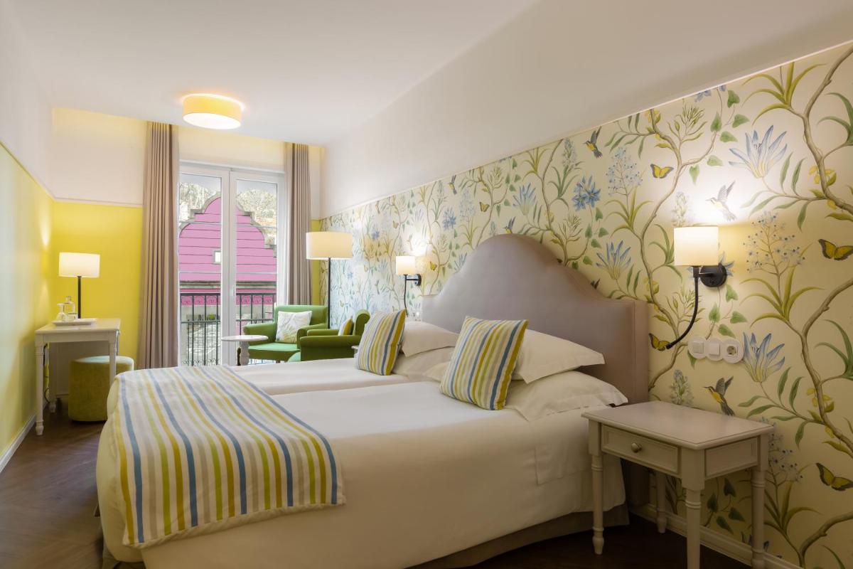 um quarto de hotel com uma cama e uma sala de estar em Castanheiro Boutique Hotel no Funchal um quarto de hotel com uma cama e uma sala de estar em Castanheiro Boutique Hotel no Funchal