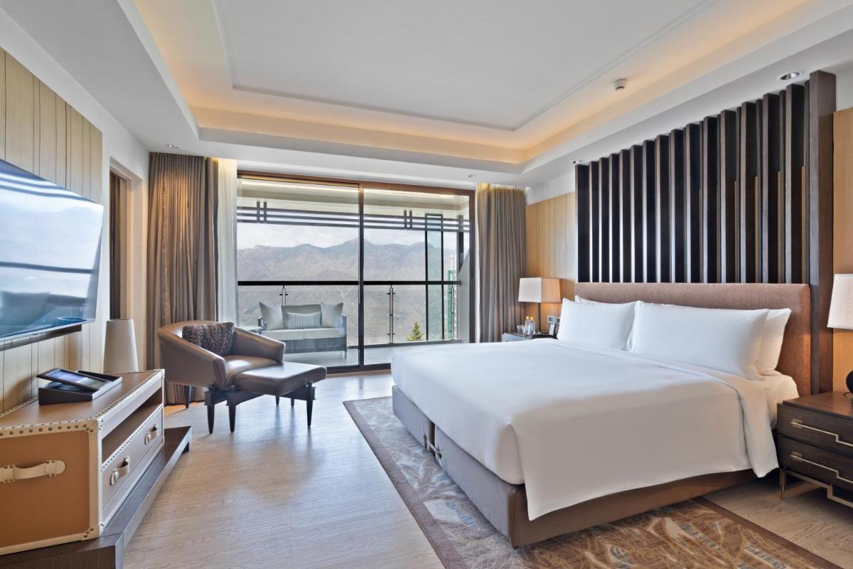 a bedroom with a large bed and a large window at JW Marriott Mussoorie Walnut Grove Resort & Spa in Mussoorie