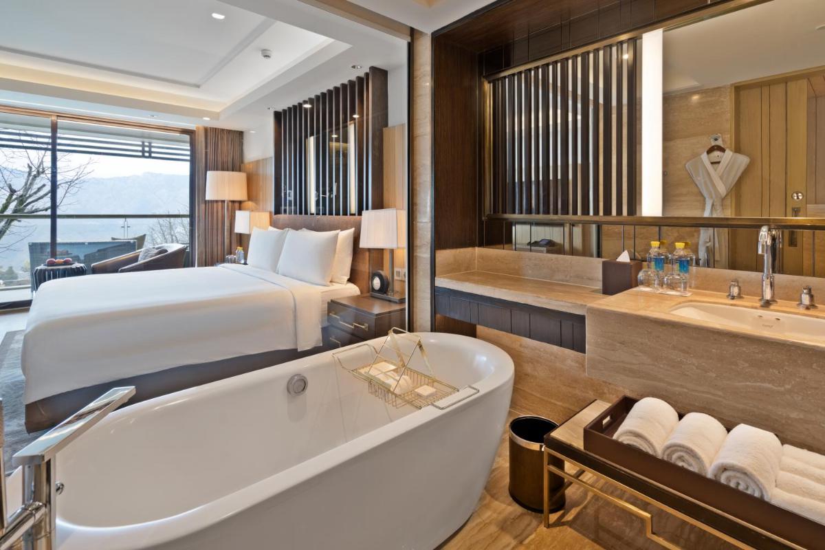 a bedroom with a bed and a bath tub and a bed and a bath tub at JW Marriott Mussoorie Walnut Grove Resort & Spa in Mussoorie
