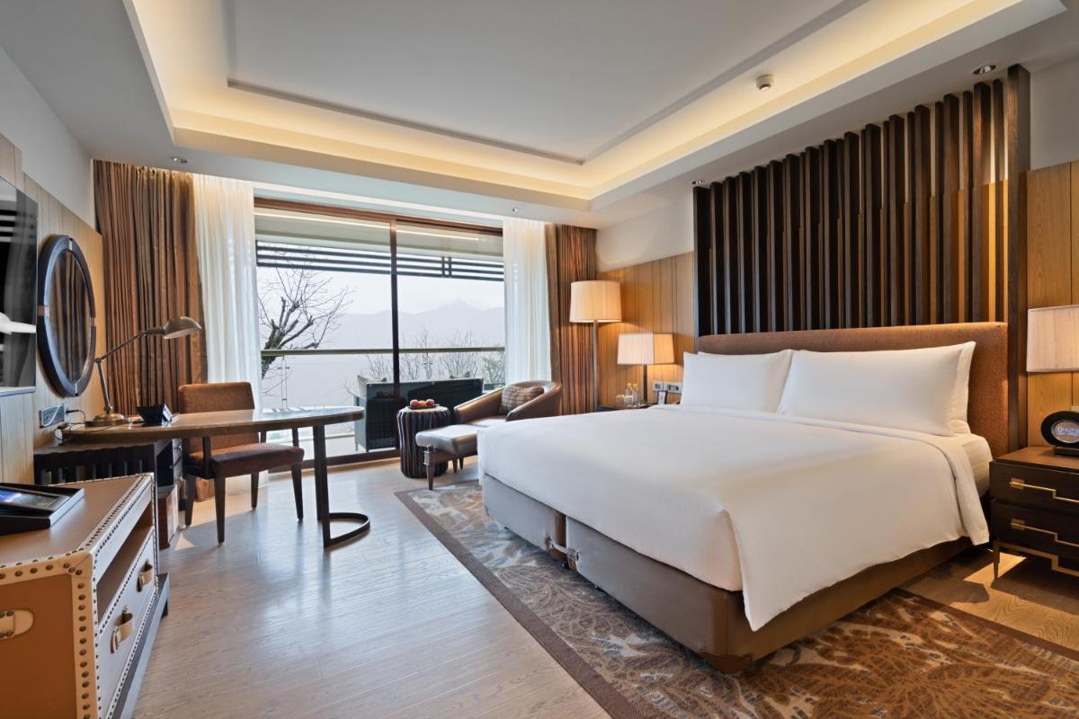a hotel room with a large bed and a desk at JW Marriott Mussoorie Walnut Grove Resort & Spa in Mussoorie