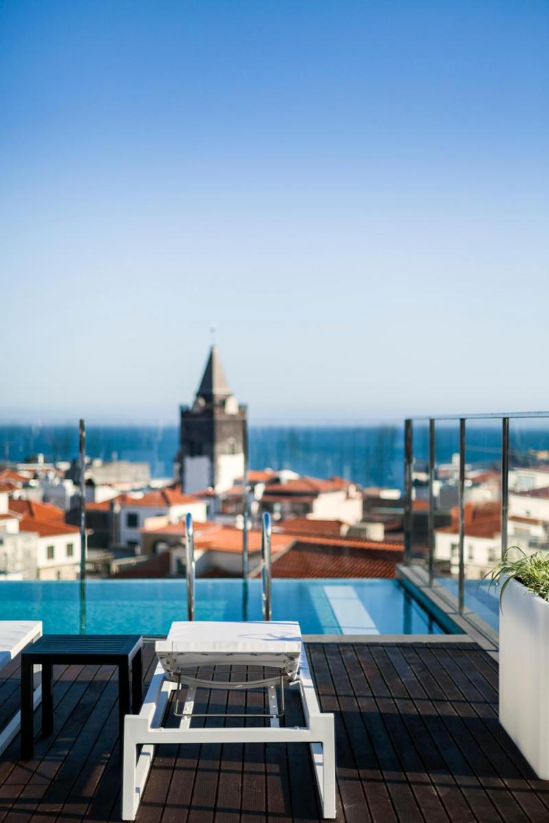 uma varanda com uma mesa e vista para uma cidade em Castanheiro Boutique Hotel no Funchal uma varanda com uma mesa e vista para uma cidade em Castanheiro Boutique Hotel no Funchal