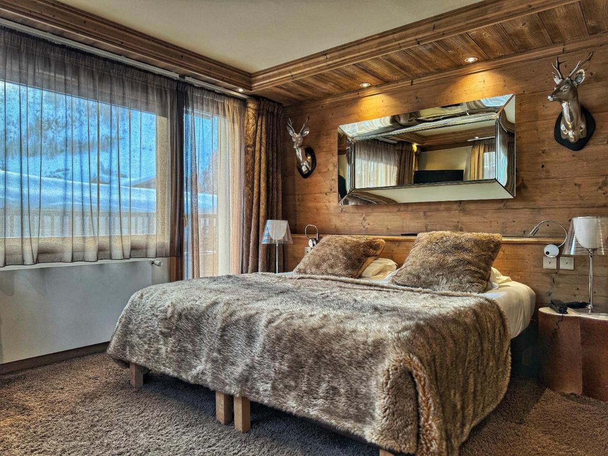une chambre avec un grand lit et un miroir dans l'établissement Hotel Tsanteleina, à Val dʼIsère