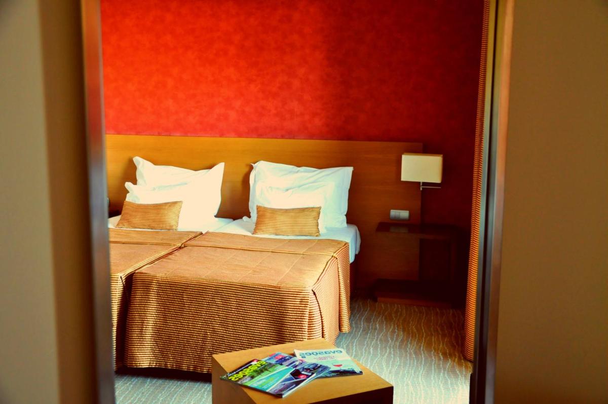 um quarto de hotel com uma cama e uma parede vermelha em Hotel Lusitania Congress & Spa na Guarda