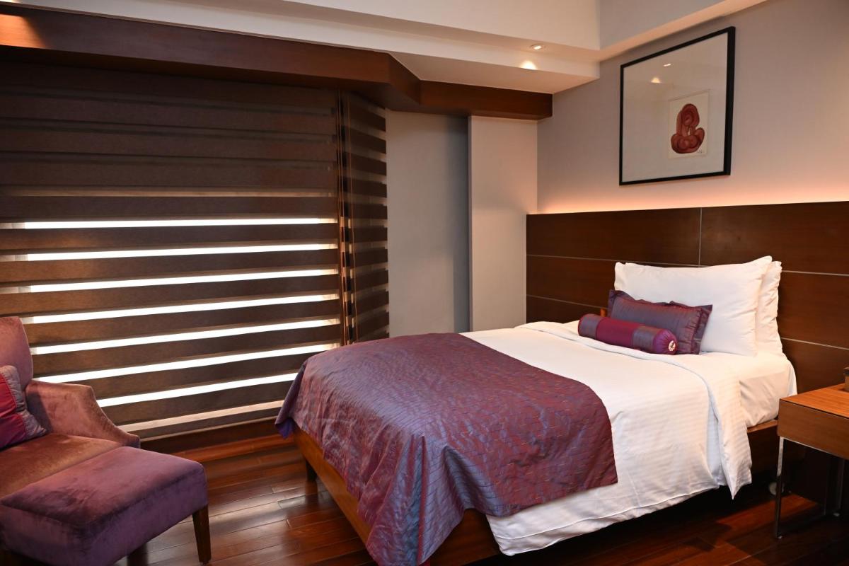 a bedroom with a large bed and a chair at The LaLiT New Delhi in New Delhi
