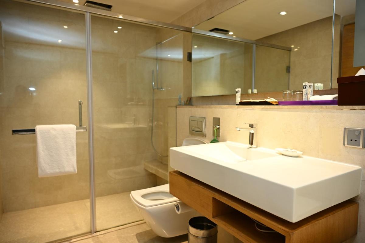 a bathroom with a sink and a shower and a toilet at The LaLiT New Delhi in New Delhi