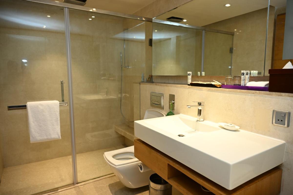 a bathroom with a sink and a shower and a toilet at The LaLiT New Delhi in New Delhi