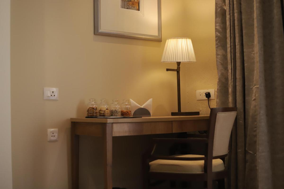 a desk in a hotel room with a lamp and a chair at Essentia Luxury Resort & Spa Udaipur in Udaipur