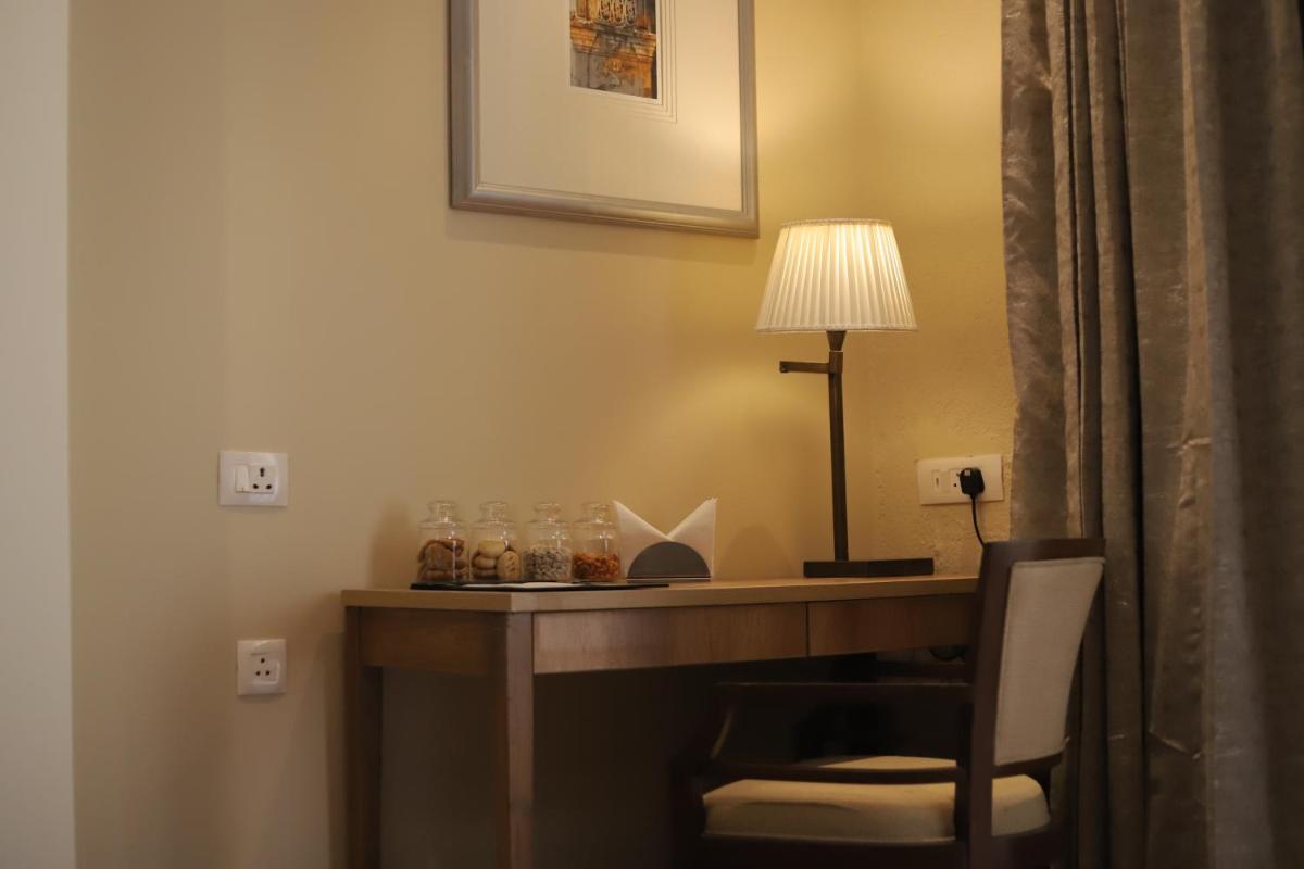 a desk in a hotel room with a lamp and a chair at Essentia Luxury Resort & Spa Udaipur in Udaipur