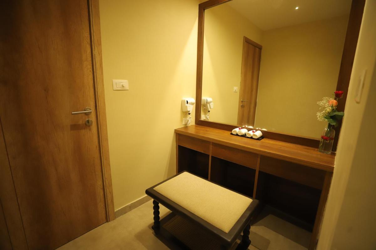a bathroom with a vanity with a mirror and a stool at Essentia Luxury Resort & Spa Udaipur in Udaipur