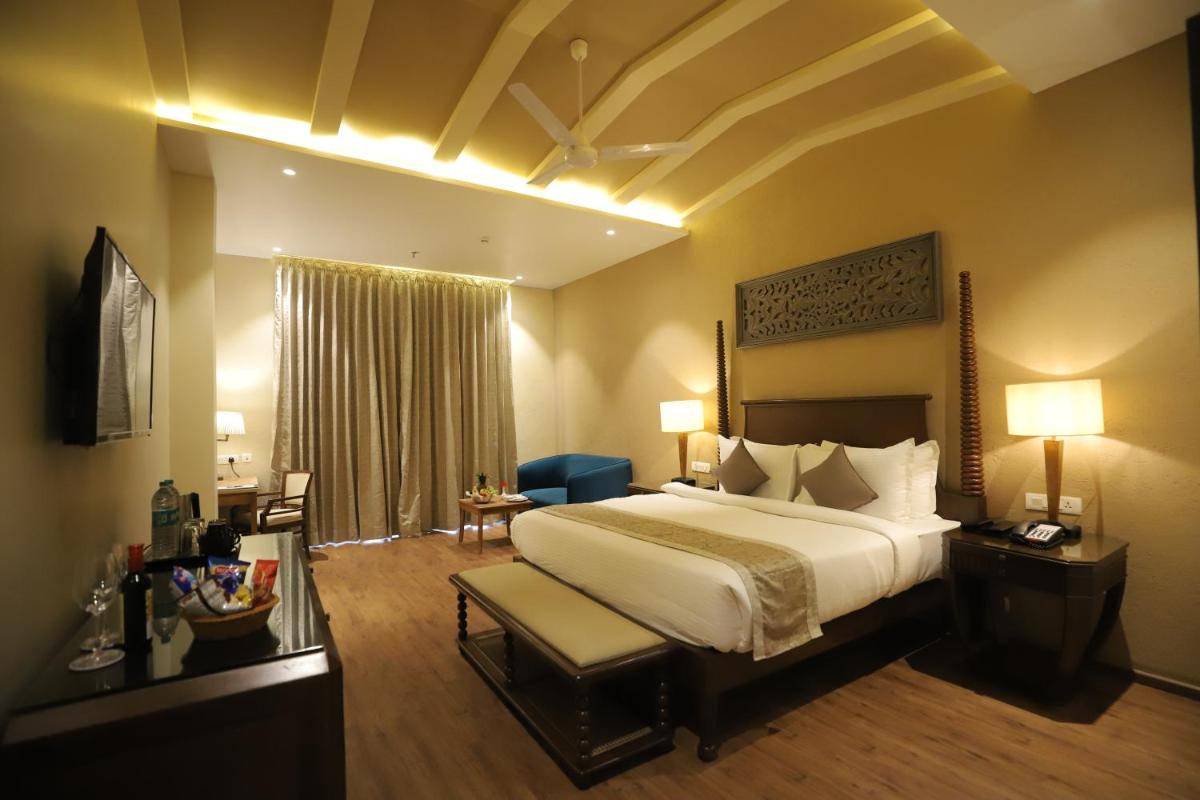 a hotel room with a large bed and a desk at Essentia Luxury Resort & Spa Udaipur in Udaipur