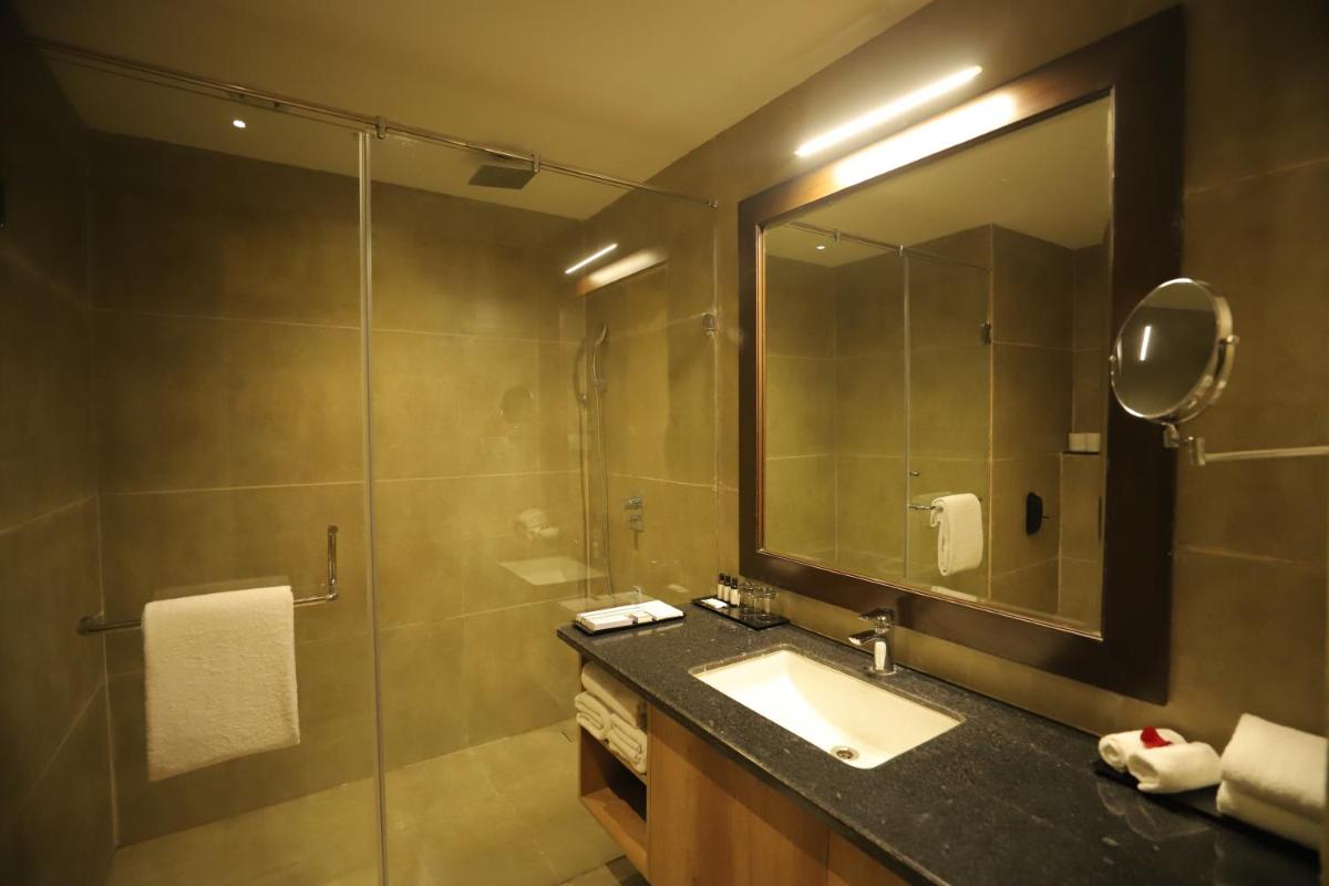 a bathroom with a sink and a shower with a mirror at Essentia Luxury Resort & Spa Udaipur in Udaipur