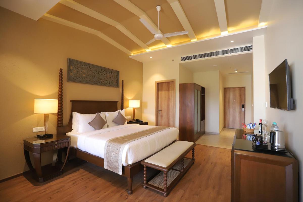 a bedroom with a bed and a desk and a television at Essentia Luxury Resort & Spa Udaipur in Udaipur