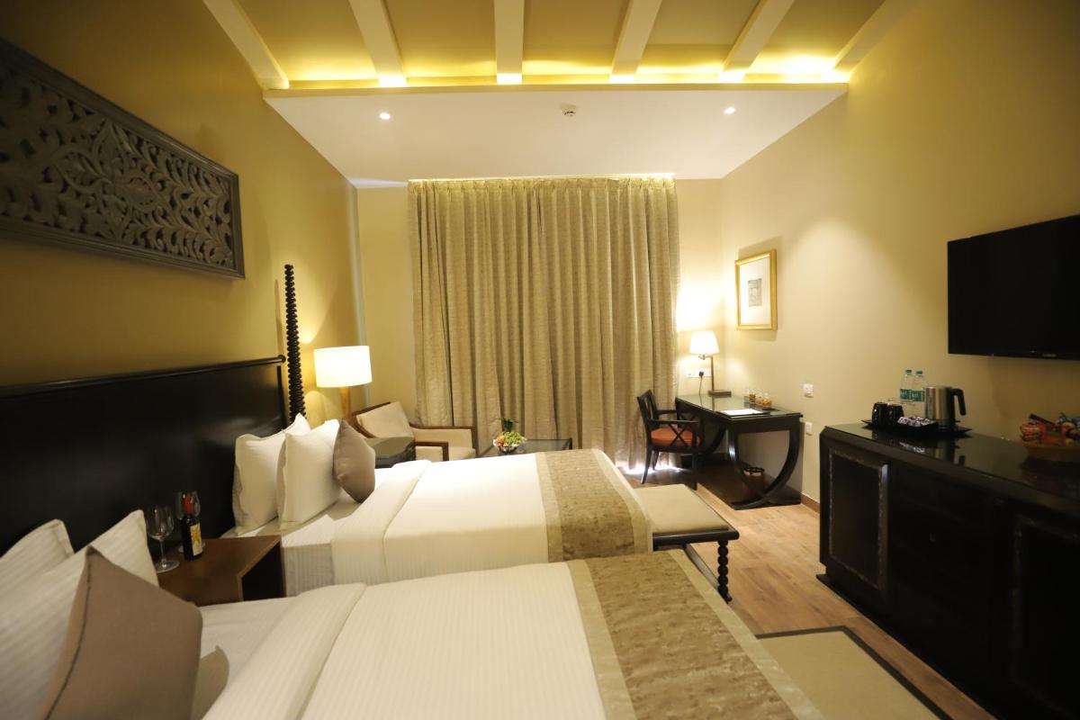 a hotel room with two beds and a television at Essentia Luxury Resort & Spa Udaipur in Udaipur