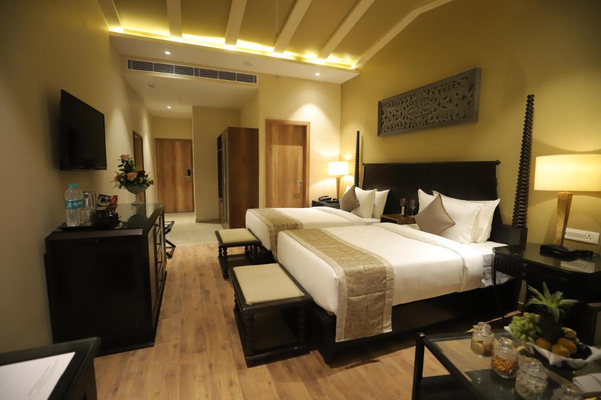 a hotel room with a large bed and a television at Essentia Luxury Resort & Spa Udaipur in Udaipur