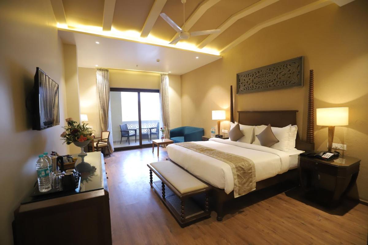 a hotel room with a large bed and a living room at Essentia Luxury Resort & Spa Udaipur in Udaipur