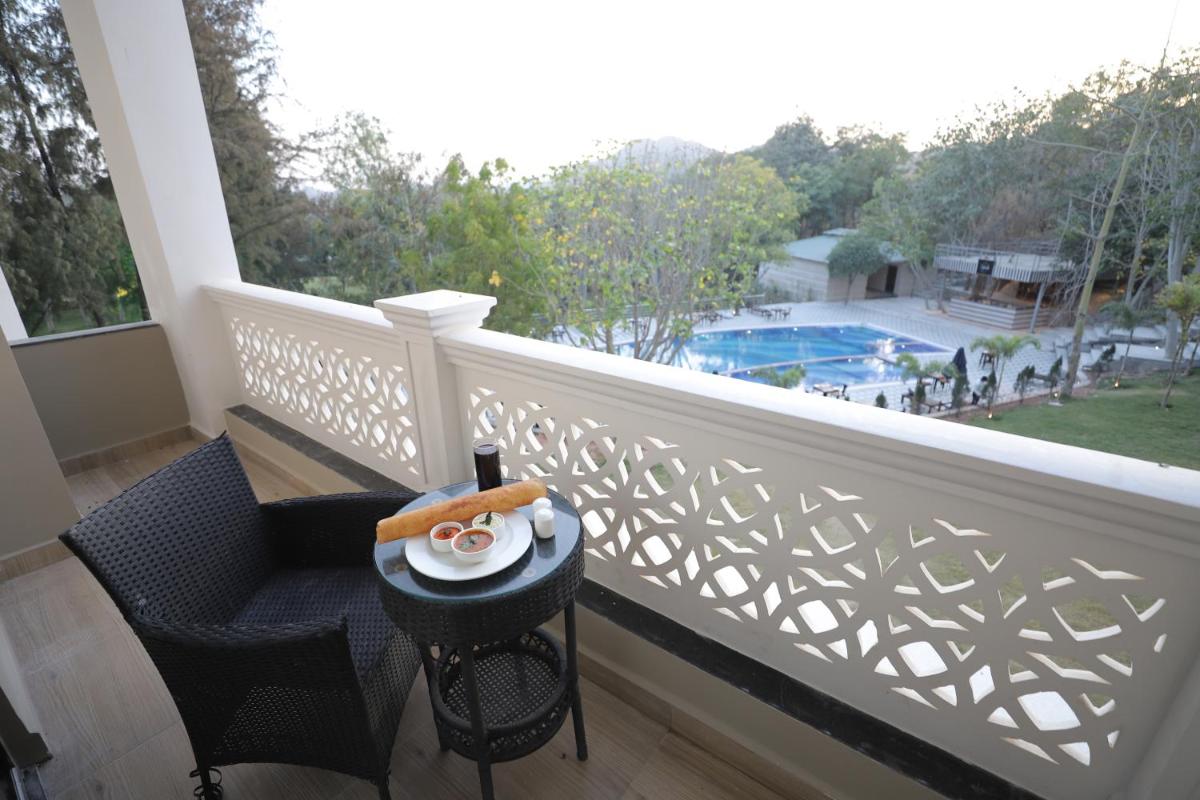 a balcony with a table with a plate of food on it at Essentia Luxury Resort & Spa Udaipur in Udaipur