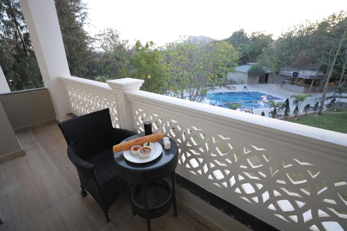 a balcony with a table and a view of a pool at Essentia Luxury Resort & Spa Udaipur in Udaipur