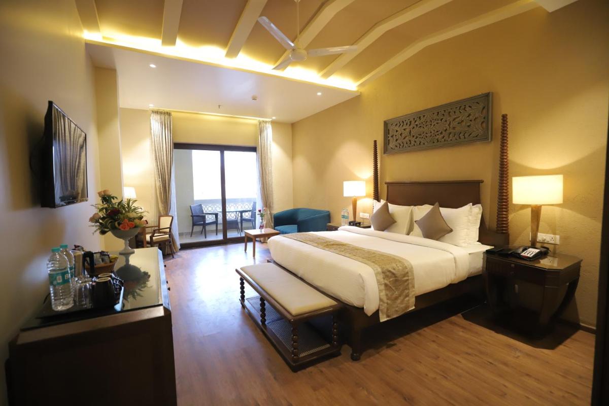 a hotel room with a large bed and a living room at Essentia Luxury Resort & Spa Udaipur in Udaipur
