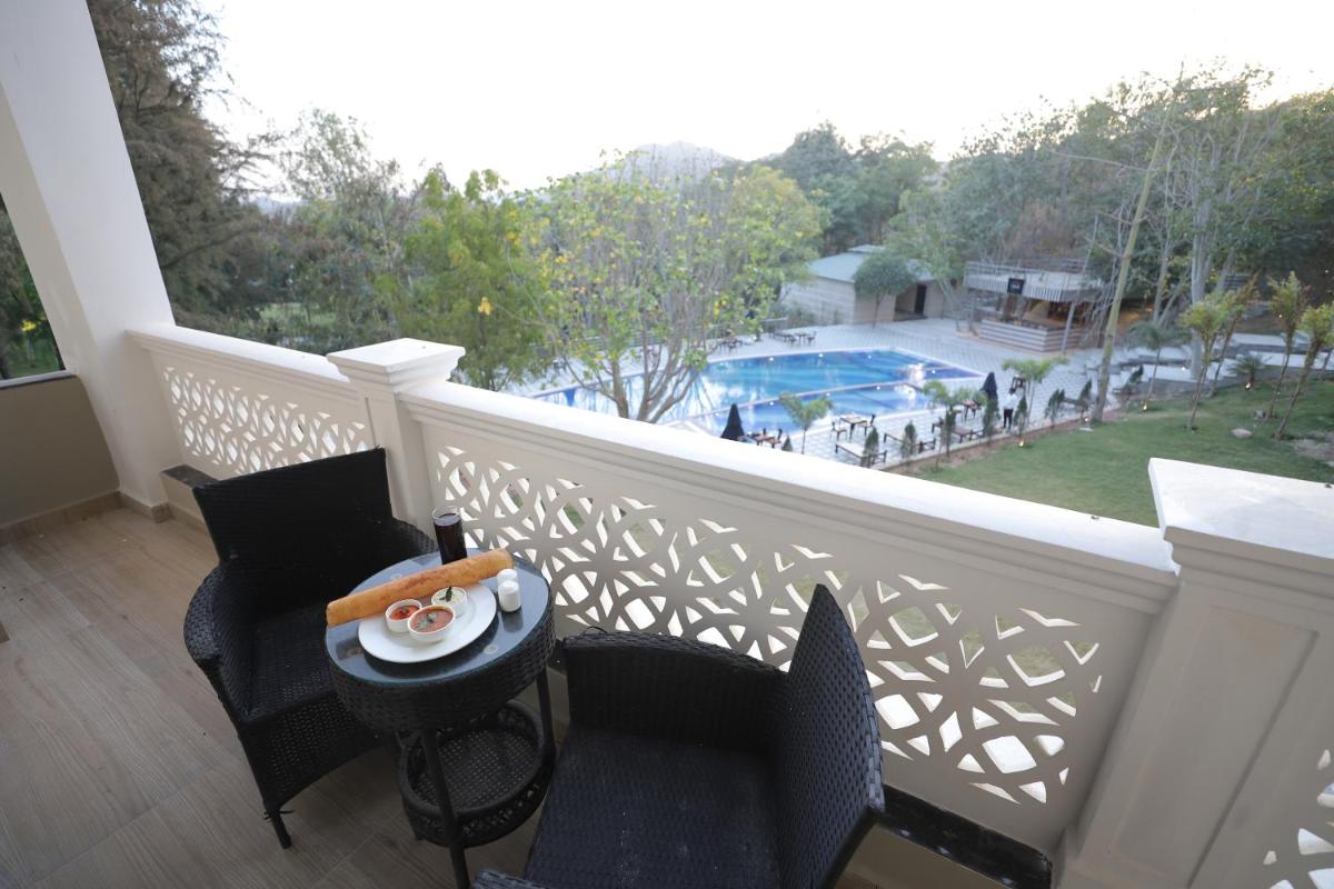 a balcony with two chairs and a table with a plate of food at Essentia Luxury Resort & Spa Udaipur in Udaipur