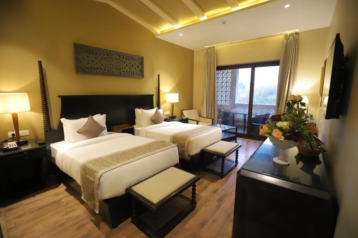 a hotel room with two beds and a large window at Essentia Luxury Resort & Spa Udaipur in Udaipur
