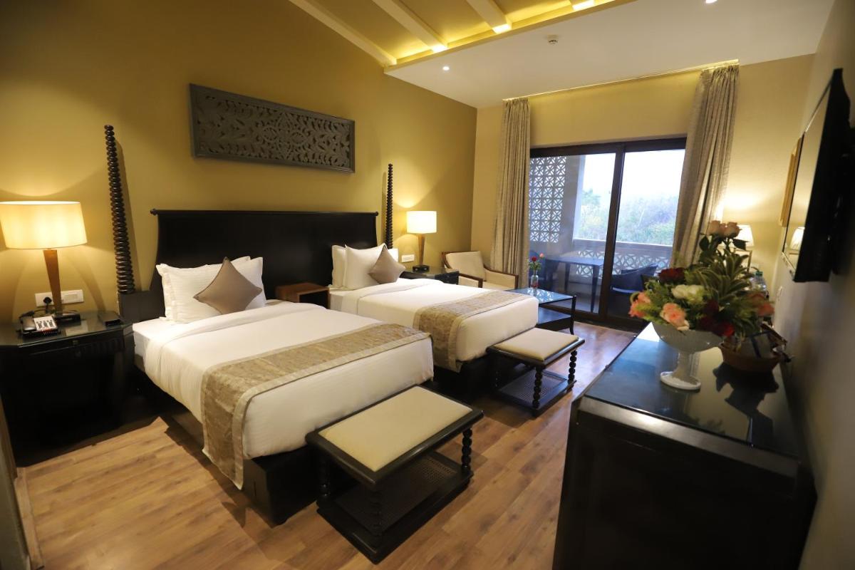 a hotel room with two beds and a large window at Essentia Luxury Resort & Spa Udaipur in Udaipur